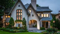 a white house with lots of windows and plants in the front yard at night time