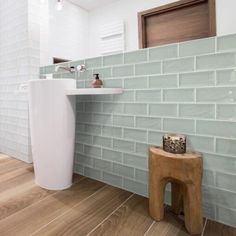 a bathroom with wood flooring and white tiles on the walls, along with a pedestal sink