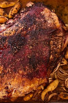 a large piece of meat sitting on top of a table next to some bananas and potatoes