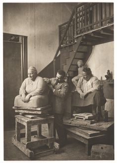 an old black and white photo of three people sitting in front of a stair case