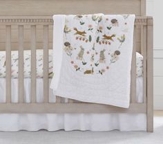 a baby crib with a white blanket on top of it and an animal themed bedding