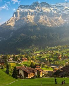 the mountains are covered in snow and green grass, with houses on either side of them