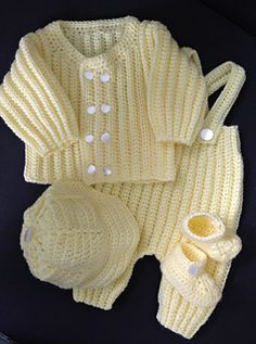 a knitted baby outfit and booties on a black surface