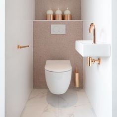 a white toilet sitting in a bathroom next to a wall mounted faucet and sink