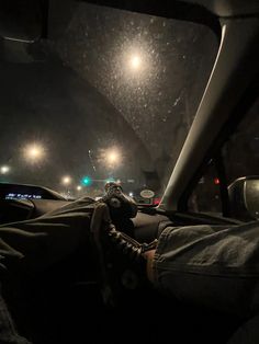 someone is sitting in the passenger seat of a car at night with their feet on the dashboard