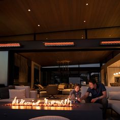 two people sitting in front of a fire pit with the lights on and one person looking at it