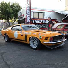 an orange muscle car parked in front of a building