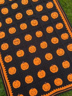 a crocheted blanket with pumpkins on it sitting in the middle of grass