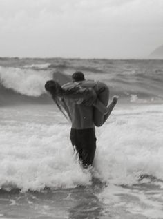 a man is carrying his surfboard into the ocean while holding on to it's back