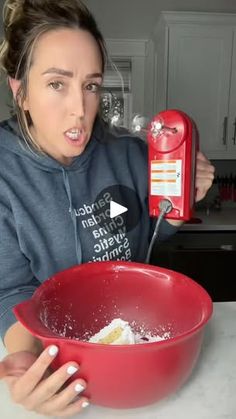 a woman holding a red bowl with something in it