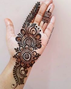 a woman's hand with henna tattoos on it, showing the intricate design