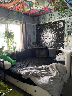 a bedroom with an unmade bed and plants hanging from the ceiling, in front of a window