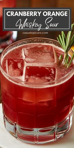 a cranberry orange whiskey sour cocktail with rosemary garnish on the rim