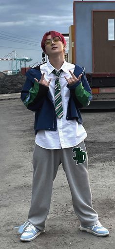 a young boy wearing a tie and jacket standing in front of a train car with his hands up