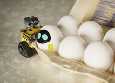 an egg carton filled with white eggs and a toy truck sitting in it's back