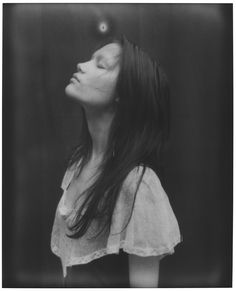 a black and white photo of a woman with her eyes closed looking up to the sky