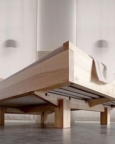 a wooden bed frame sitting on top of a hard wood floor next to white walls