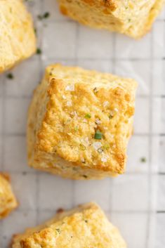 several biscuits sitting on top of a wire rack next to some green onions and parsley