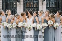 a group of women standing next to each other in front of a building holding bouquets