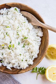 white rice in a wooden bowl with lemon wedges and parsley on the side