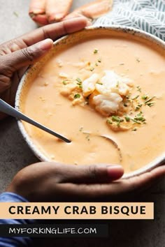 two hands holding a bowl of creamy crab bisque