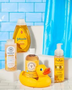 a yellow rubber duck sitting on top of a bath tub next to bottles of soap