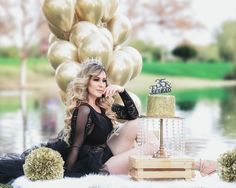 a woman sitting on the ground with a cake in front of her and balloons behind her