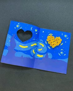 an open book with a heart shaped hole in the middle and blue paper on top