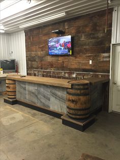 a bar made out of wooden barrels with a tv mounted on the wall behind it