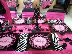 a table set up with pink and black plates, zebra print napkins and place settings