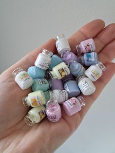 a hand holding a bunch of small bottles in it's palm with the top one filled with them