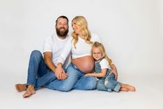 a man and woman sitting next to each other on the floor with their baby bump up