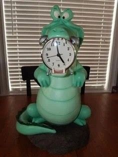 a green frog clock sitting on top of a wooden table