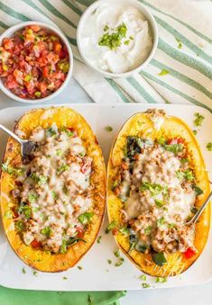 two stuffed squash halves with meat and veggies in the middle on a serving tray