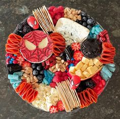 a platter with cheese, crackers, fruit and spiderman face on it