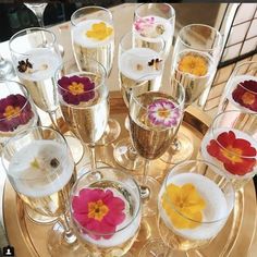 there are many wine glasses with flowers in them on the tray and one is filled with champagne