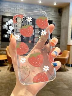 a woman holding up her phone case with strawberries on it