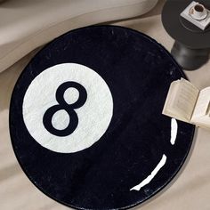 a black and white round rug with the number eight on it next to an open book