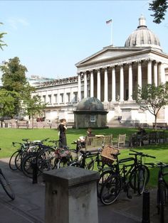 many bicycles are parked in front of a large building with pillars and columns on it