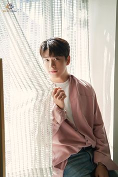 a young man sitting in front of a window