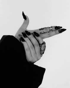 black and white photograph of woman's hands with rings on their fingers, holding something in the air