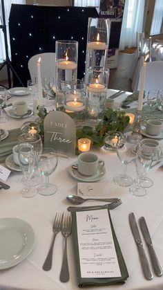 the table is set with silverware, candles and place settings for an elegant dinner