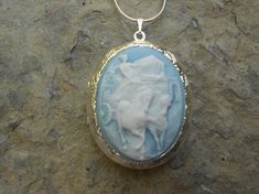 Beautiful Grecian Charioteer cameo locket!!!  The cameo is a gorgeous white on sky blue, beautifully detailed!!!  The locket is victorian style with beautiful scroll on the front and back about 1 3/4" long.  It can hold two photos, keepsakes, or even your daily medication or vitamins!!! Pass down from generation to generation!!! The chain is 22"  1.2mm .925 plated snake chain with a lobster claw clasp!!! Perfect  for Brides or Bridal parties.  Makes a unique memorable gift for any occasion!!!  T Blue Locket Necklace For Wedding, Blue Medallion Necklace For Wedding, Blue Medallion Necklaces For Wedding, Victorian Blue Cameo Jewelry, Blue Cameo Jewelry For Wedding, Blue Locket Jewelry For Wedding, Blue Wedding Locket Jewelry, Blue Cameo Necklace For Wedding, Grecian Women