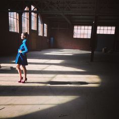 a woman is standing in an empty warehouse