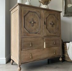 an old wooden cabinet with two doors and knobs on the bottom, in front of a mirror