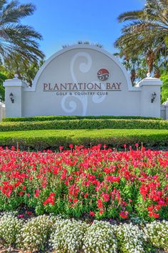 plantation bay community sign surrounded by flowers and palm trees in front of the gated entrance