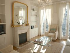 a living room filled with furniture and a fire place in front of a mirror on the wall