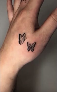 two butterflies on the palm of a woman's left hand, one is black and white