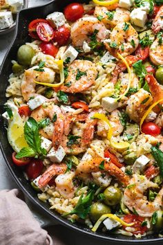 a skillet filled with shrimp, tomatoes, olives, and feta cheese