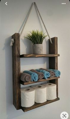 a wooden shelf with several rolls of toilet paper hanging from it's sides and two potted plants on top